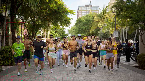 Group of runners jogging together down palm-lined street at CityPlace West Palm Beach