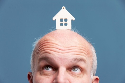 Man with house icon on head looking upward representing real estate thinking