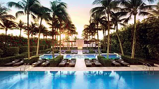 Palm-lined pool at sunset with lounge chairs at The Setai Miami Beach