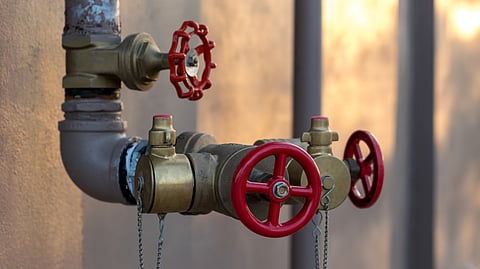 Close-up of red valve handles on metal plumbing pipes outdoors