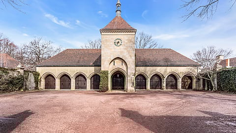 Historic stone carriage house with clock tower and arched bays in Middletown estate