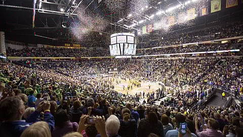Crowd celebrating inside a packed basketball arena during NCAA championship game confetti moment