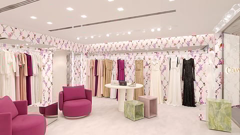 Genny boutique interior with floral walls, dresses, and pink seating