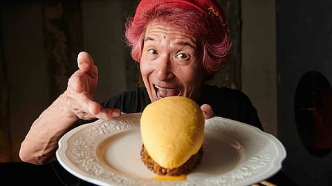 Chef Motokichi Yukimura holding omurice dish and gesturing playfully