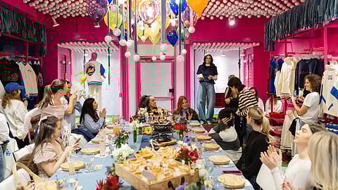 Editors seated at a long table inside TEREZ UES store surrounded by MLB apparel and colorful decor