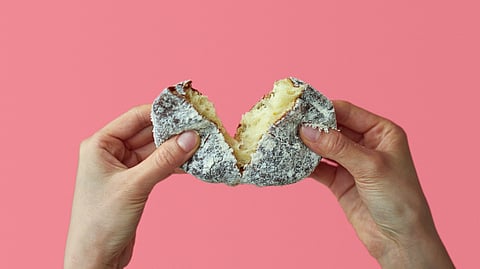 Hands breaking soft sugar-coated donut showing airy interior