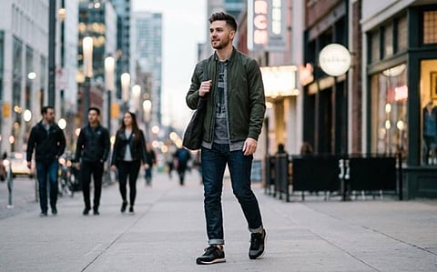 A man wearing a dark green lightweight bomber jacket