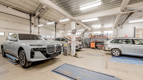 Bright auto repair shop with vehicles on lifts, tools, and workstations