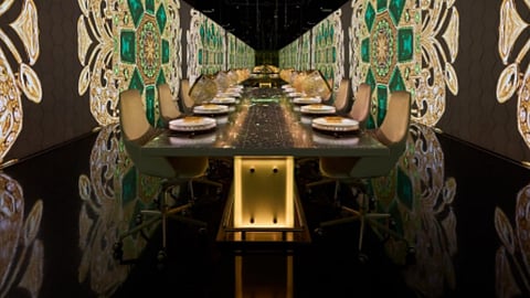 Futuristic dining room with long table and digital projections covering walls