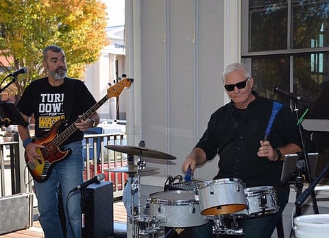Two individuals playing musical instruments during an outdoor performance