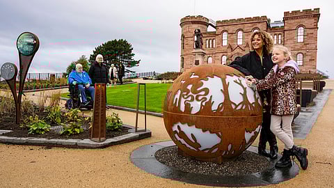 Visitors at Inverness Castle grounds with globe sculpture and historic building