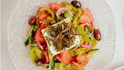 Fresh Greek salad with feta, tomatoes, cucumbers, olives, and herbs plated elegantly