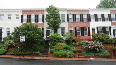 Row of townhouses on a quiet residential street with greenery and sidewalks