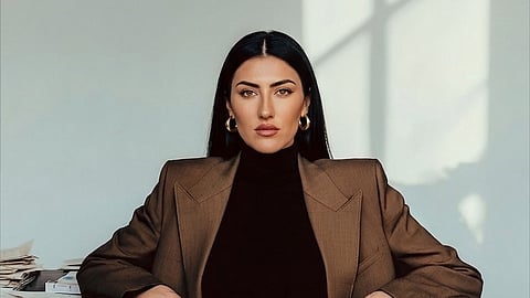 Antonella Attorre seated in tailored suit at desk with papers, minimalist interior setting
