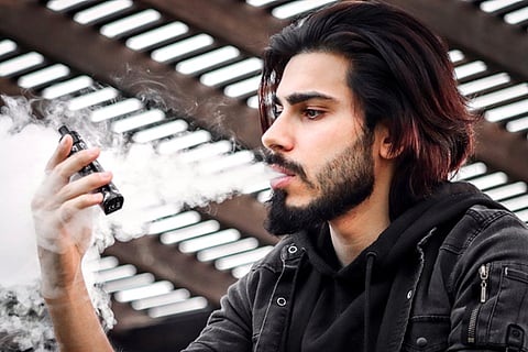 a man holding and vaping from an electronic device