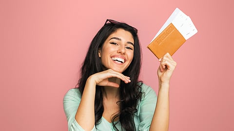 Woman holding passport and tickets over suitcase, ready for travel booking and departure