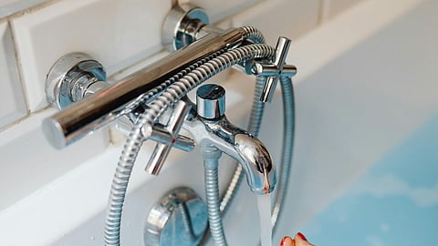 a chrome bath shower mixer tap mounted on a wall with white subway tiles