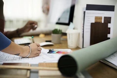 professionals working together at a desk on a design or architectural project.