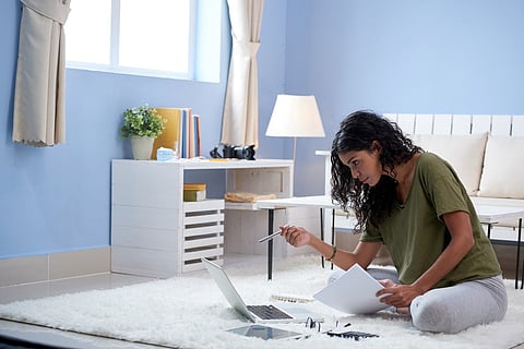 a person sitting on a rug and working on a laptop