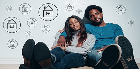 a couple sitting on the floor, symbolizing their aspirations for home ownership