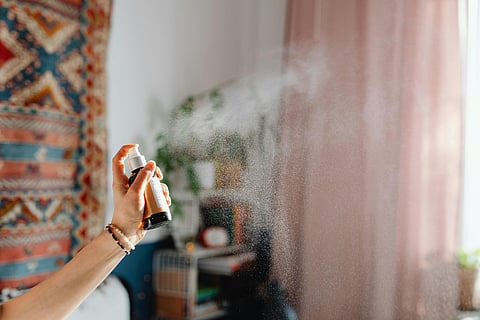 a person spraying a fragrance in a cozy room