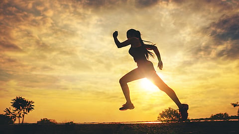 Silhouette of a woman running at sunset outdoors during a wellness workout session