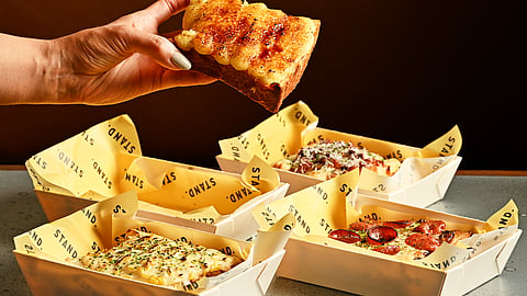 Hand holding toasted milk bread over STAND. sandos and bento trays