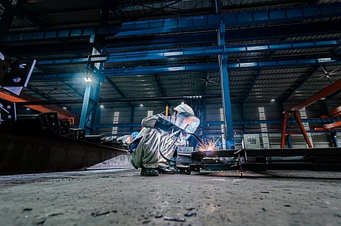 a professional welder operating in a large industrial factory setting