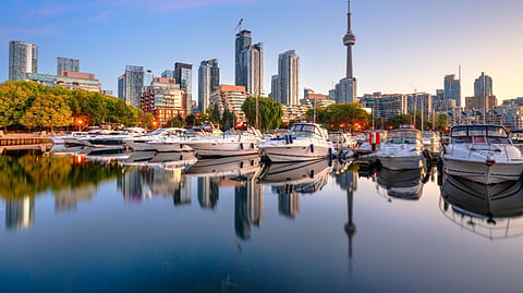 Toronto skyline and marina reflected on calm waterfront at sunset
