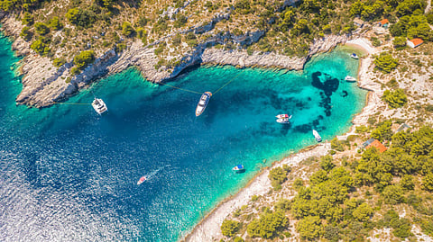 Aerial view of boats anchored in a turquoise cove on Croatia’s Central Dalmatian coast