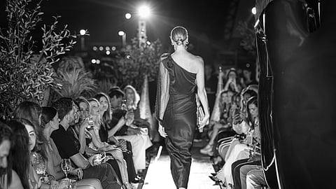 Model walks the runway in a draped evening look from The Shape of Silence collection