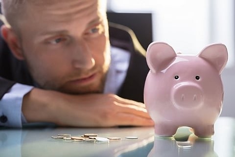 a man looking at his piggy bank