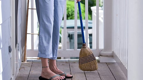 a person sweeping a wooden porch with a broom