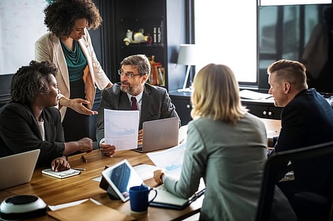 Coworkers discussing a chart during a meeting at an office desk.