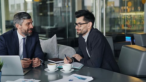 Two businessmen in suits having a conversation over coffee