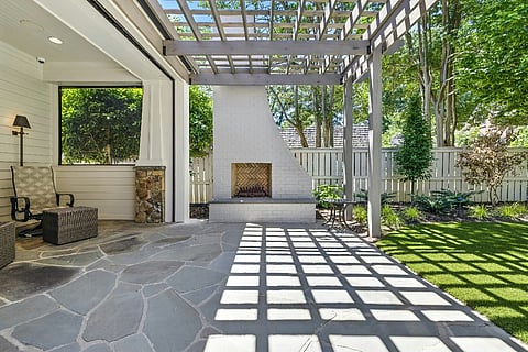 Modern outdoor patio with pergola, fireplace, seating area, and landscaped garden.