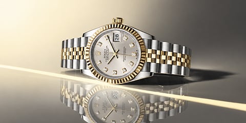 Close-up of a luxury gold and silver wristwatch on a reflective surface