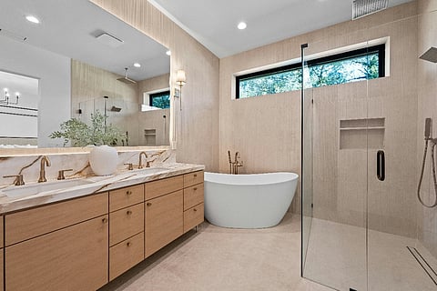 Modern luxury bathroom with freestanding bathtub, glass shower, and wooden vanity.