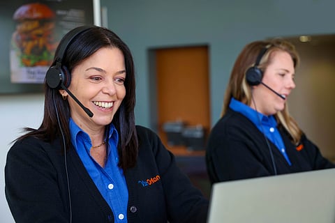 two individuals wearing professional headsets, likely working as vacation planners for Visit Orlando