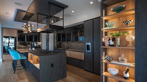 Modern luxury kitchen with dark cabinetry and illuminated shelving.