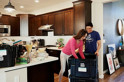 Couple packing reusable moving boxes in a kitchen.