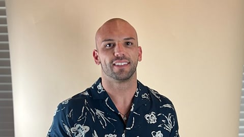Bald man wearing a navy floral shirt.