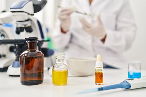 A woman in a lab coat holds a bottle of medicine