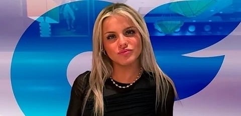 A woman wearing a black dress appears on television, speaking confidently to the audience.