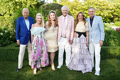 Group of six gala guests posing together on a lawn