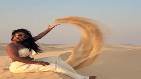 Woman throwing sand in a desert.