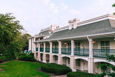 White building with columns and green balconies.