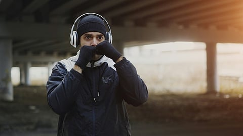 Man shadow boxing under a bridge