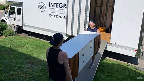 Movers loading a dresser into a truck.