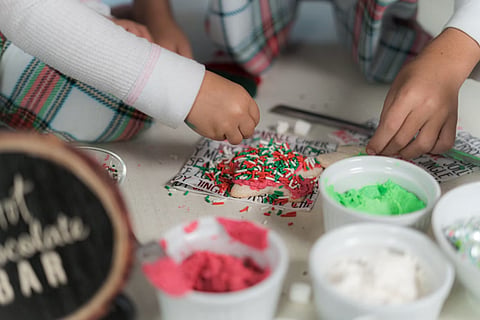 Children decorating cookies with sprinkles.